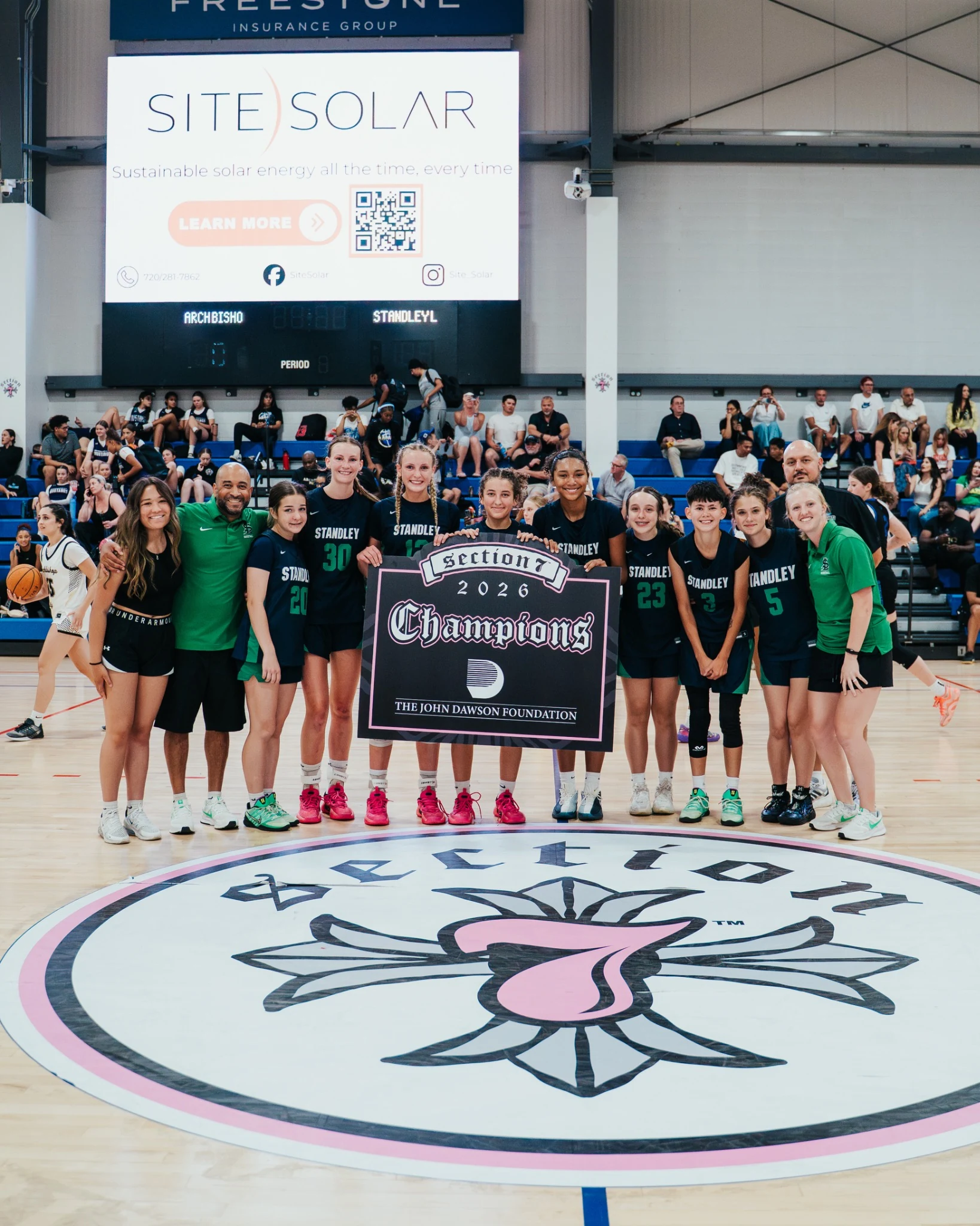 Girls basketball team celebrating together on the court