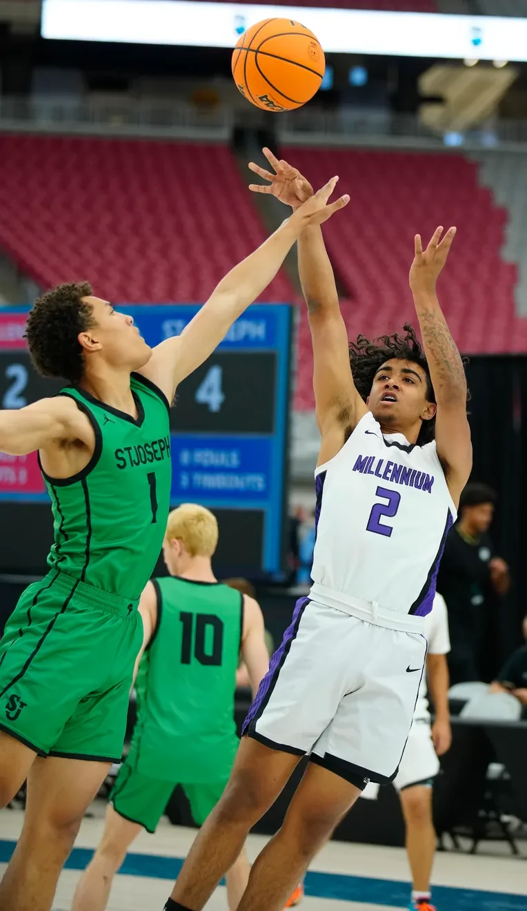 A boys basketball player shooting over a defender