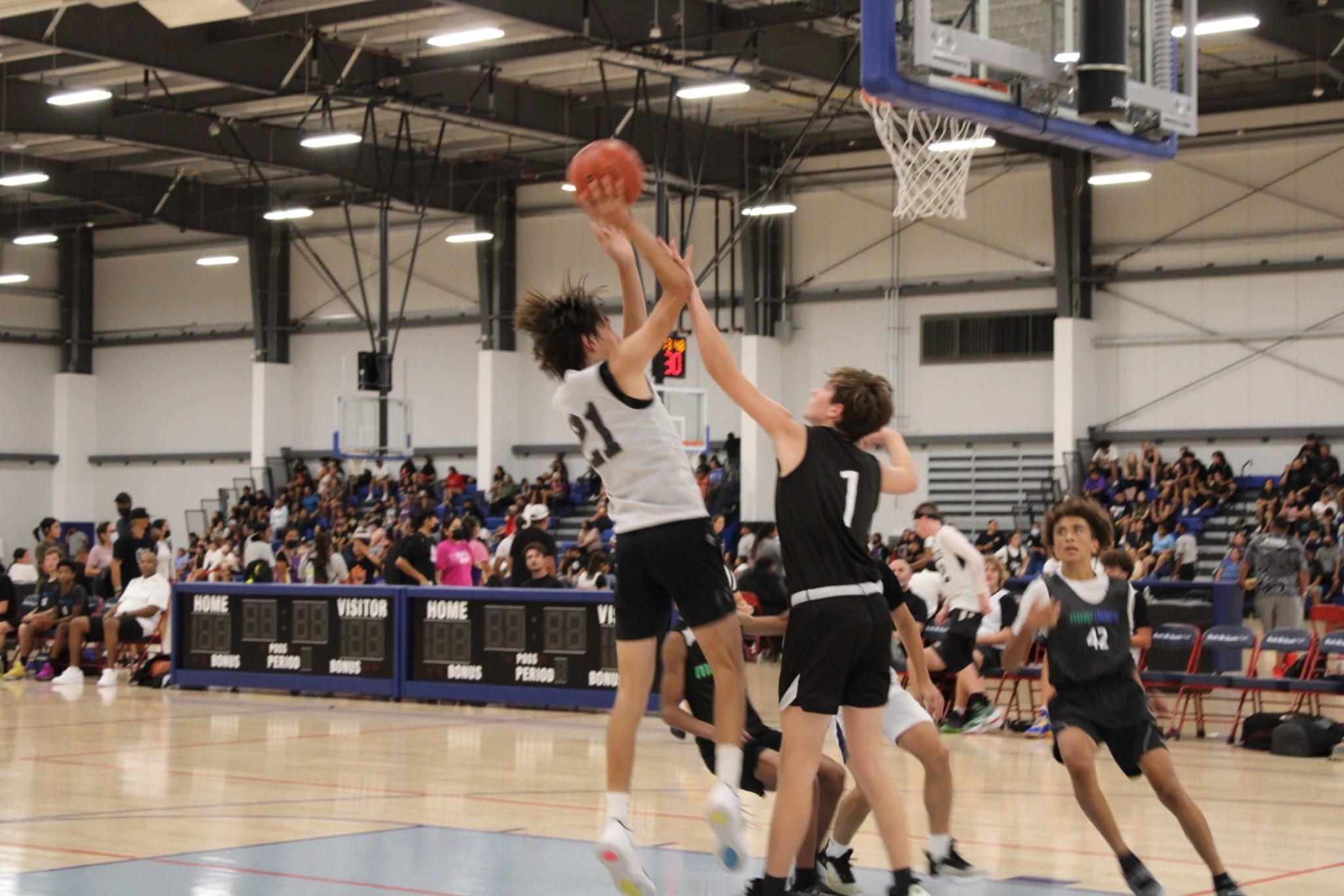 Basketball action and courtside spectators inside the event venue