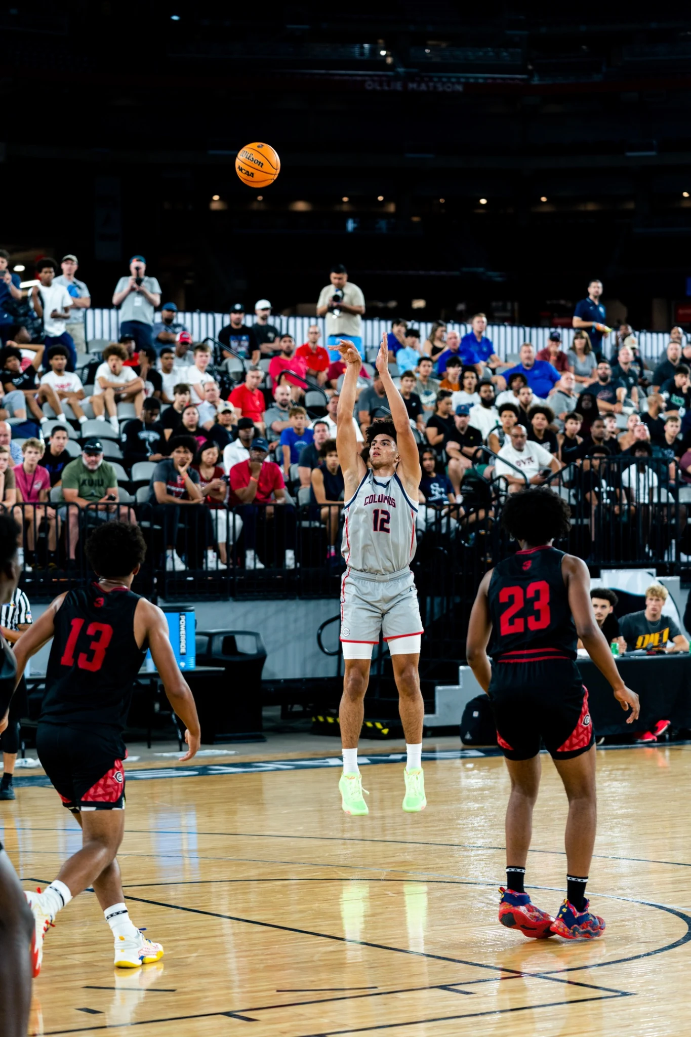 A basketball player shooting in front of a full courtside crowd at Section 7